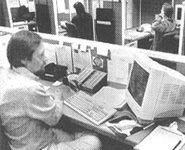 Black and white photo of a man working in front of a computer monitor.